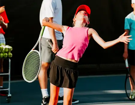 Girl serving tennis ball