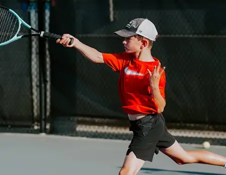 Boy hitting tennis ball